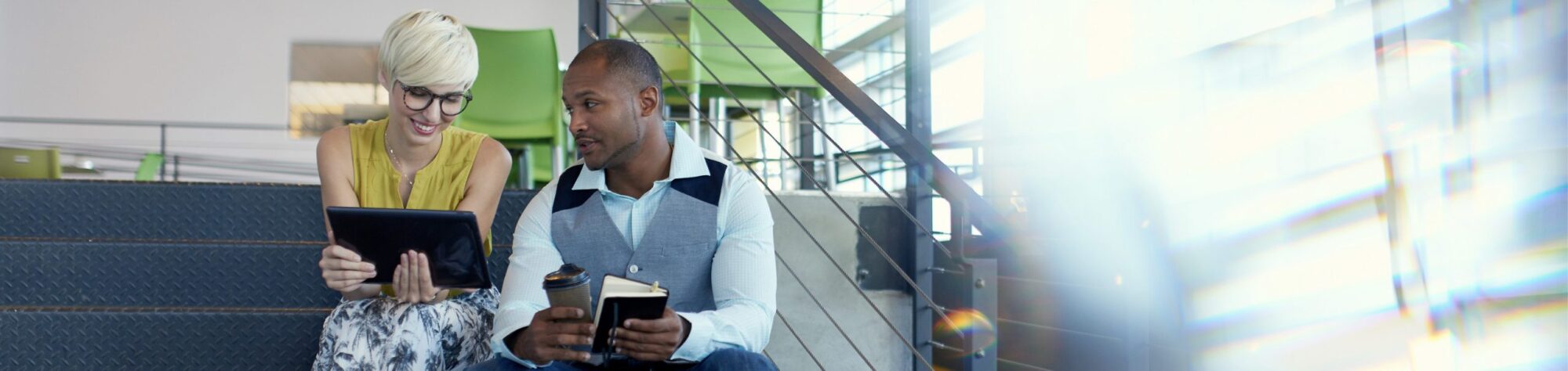 Man and woman sitting on steps looking at tablet